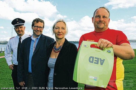 Von links: Wehrführer Jan Peter Dohrendorf, Jörg Peters von der Schleswig-Holstein Netz AG, Dagmar Timm von der DLRG Pogeez-Holstentorf und Wachleiter Stefan Krey mit dem neuen Defibrillator.